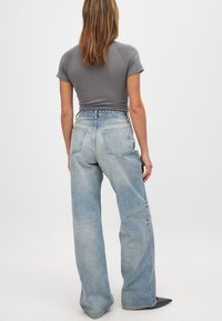 Pelēks piegriezuma t-krekls, gaiši zili platā stila džinsi ar augstu jostasvietu, klasiskas džinsu auduma, pieci kabatas, minimālistisks dizains, saplēstas apakšmalas detaļas.