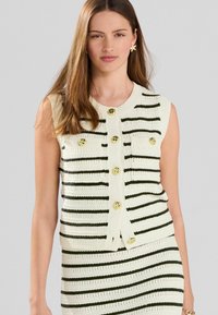 Cardigan senza maniche a maglia a righe crema e verde scuro, con bottoni dorati e scollo rotondo con bordi a coste.