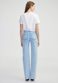 Lichtblauwe jeans van denim met een hoge taille, wijde pijpen en een subtiele textuur. Beschikt over achterzakken en een ritssluiting.