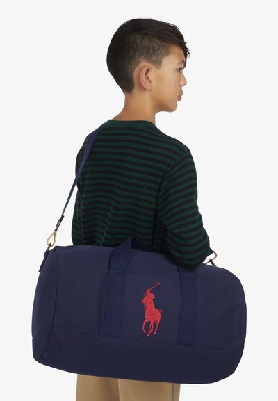 Bolsa de lona azul marino con logo rojo de jugador de polo, confeccionada con tela duradera, cuenta con asas dobles y una correa de hombro desmontable.