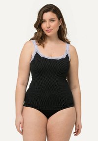 Top sin mangas de lunares negros con detalles de encaje en azul claro. Tirantes finos y diseño ajustado, combinado con ropa interior negra sólida.