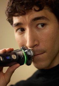 Rasoi elettrico Philips, nero con accenti metallici, presenta una luce LED verde, una testina da barba arrotondata e un'impugnatura ergonomica per un uso preciso.