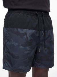 Mann trägt schwarze und dunkelblaue Shorts mit Camouflage-Muster, elastischem Bund und schwarzen Kordeln.