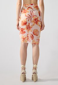 Blomstrete midi-skjørt med livlige oransje og gule blomster og skjell på en lys bakgrunn, med en tettsittende design og elastisk midjebånd.