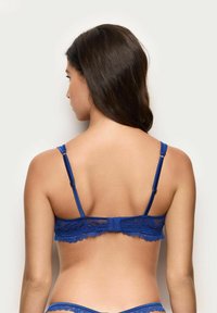 Niebieski biustonosz koronkowy z regulowanymi ramiączkami i zapięciem na hak i oczko. Posiada falbany na krawędziach oraz półprzezroczysty tył.