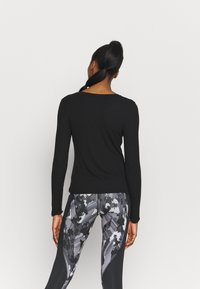 Czarna bluzka z długim rękawem i okrągłym dekoltem, zestawiona z legginsami w odcieniach szarości i czerni, z fakturowanym wzorem.