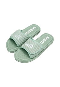 Sandales en caoutchouc vertes avec une bride nervurée, une semelle intérieure texturée dotée de trous de drainage et un logo blanc sur la bride supérieure.