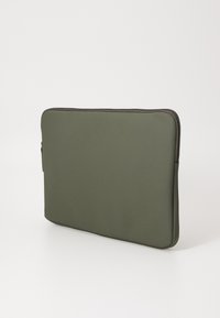 Green laptop sleeve made of soft fabric with a smooth texture. Features a zipper closure and a minimalist design with rounded edges.