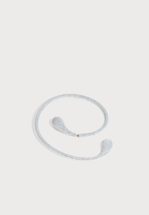 Bandeau flexible argenté pailleté avec des extrémités en forme de goutte, présenté sur un fond gris clair.