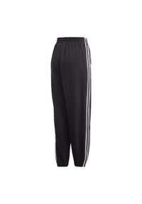 Svarta sweatpants med elastisk midja, design med avsmalnande ben och tre vita ränder längs sidorna. Mjukt material med en jämn textur.