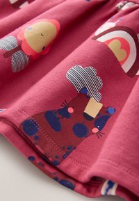 Lyserødt bomuldsstof med legesyge dyre- og regnbueprints. Indeholder en rød bjørn, en stribet sky og farverige accenter. Blød tekstur.