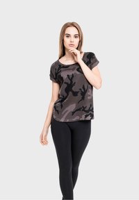 Camo print short-sleeve t-shirt in shades of grey and black, relaxed fit, round neckline, paired with black leggings.