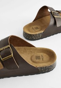 Braune Leder-Slipper mit einem breiten Riemen und einer bronzefarbenen Schnalle, ausgestattet mit einer Korktextur-Sohle und einer samtähnlichen Innensohle.