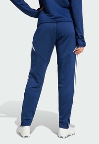 Marineblaue Jogginghosen mit weißen Seitenstreifen, schmalem Design, glatter Textur und Reißverschlussärmel. Geeignet für Freizeit- oder Sportbekleidung.