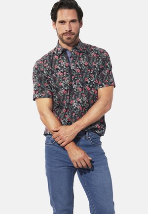 Kurzarmhemd mit Knopfleiste, das einen schwarzen Hintergrund mit floralen Mustern in Pink und Grün aufweist. Der Stoff wirkt leicht und glatt.