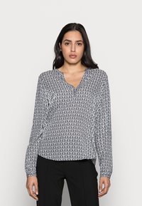 Blusa a maniche lunghe in bianco e nero, con un motivo geometrico a foglie, scollatura a V e tessuto leggero. Vestibilità rilassata con maniche a polsino.