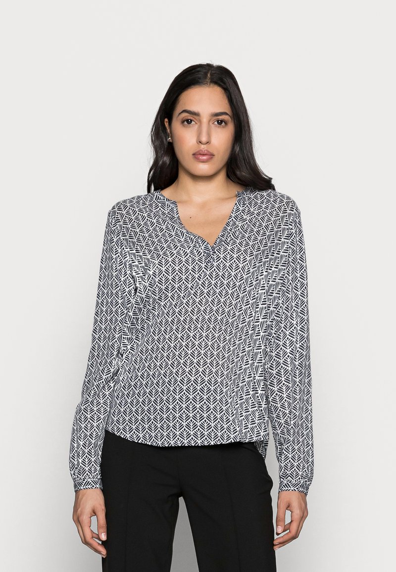 Blusa a maniche lunghe in bianco e nero, con un motivo geometrico a foglie, scollatura a V e tessuto leggero. Vestibilità rilassata con maniche a polsino.