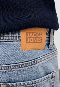 Τζιν παντελόνια από τζιν σε ανοιχτό μπλε χρώμα, με δερμάτινο ετικέτα που αναγράφει "JACK & JONES" και αντίθετη κίτρινη ραφή.