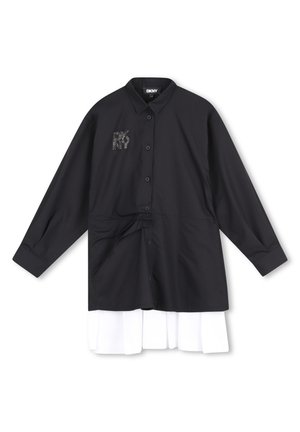Camisa negra de manga larga con botones y cuello, logo de DKNY en piedras de strass en el pecho, superpuesta sobre un tejido plisado blanco en la parte inferior.