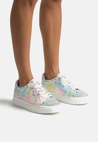 Zapatillas iridiscentes con un patrón texturizado similar al cocodrilo; acentos plateados, cordones rosa y una punta con tachuelas; suela de goma blanca.