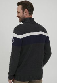 Pulover tricotat de culoare gri închis, cu guler înalt, având dungi orizontale albe și bleumarin pe partea superioară. Manșete și tiv cu textură ribbată.