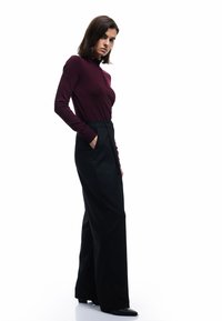 Bordeaux lange mouwen top met een hoge halslijn en knoopdetails, gecombineerd met zwarte high-waisted wijde broek. Soepele textuur en pasvorm.