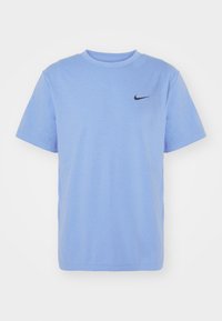 Camiseta de algodón de color azul claro con mangas cortas, cuello redondo y un pequeño logo negro de Nike en el pecho izquierdo. Textura suave, diseño casual.