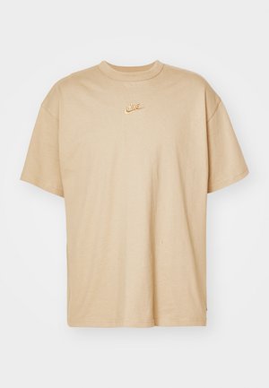 Beež puuvillane T-särk, ümmarguse kaelusega, lühikeste varrukatega ja rinnal väikese oranži tikandiga Nike logo. Veidi lõdvem istuvus.