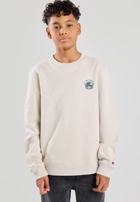 Beige sweatshirt made of soft material, featuring a round neckline, long sleeves, and a blue-accented diving helmet logo on the chest.