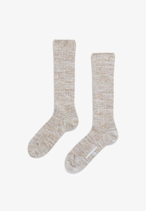 Beige ribbed socks with a textured pattern and contrasting white threads. The design features a cuff at the top and a smooth footbed.