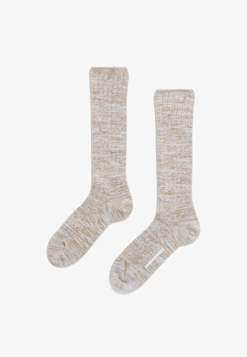 Beige gerippte Socken mit einem strukturierten Muster und kontrastierenden weißen Fäden. Das Design hat einen Bund oben und eine glatte Fußsohle.
