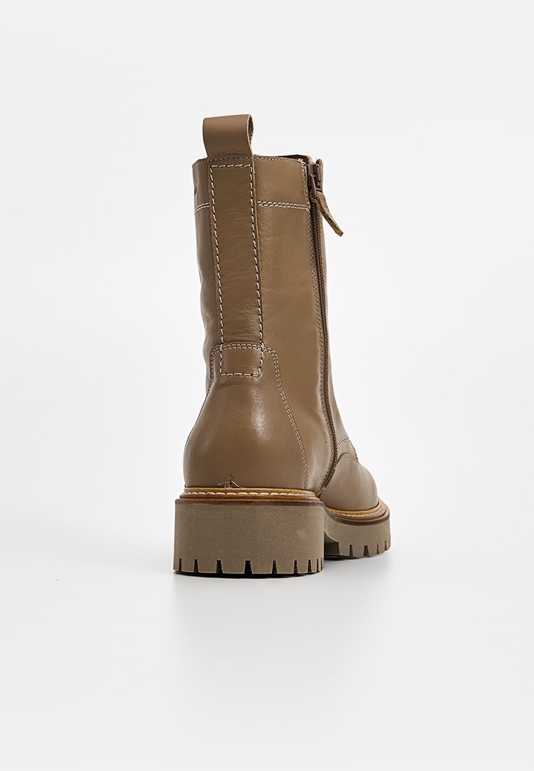 Bottes chevilles en cuir marron avec une semelle épaisse, fermeture éclair latérale et coutures contrastées. Elles possèdent un talon solide et une tige texturée.