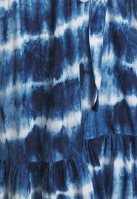 Blaue Tie-Dye-Kleid mit einer Mischung aus dunklen und hellen Blautönen, mit einem volantrim und einer Bindeschleife zur Anpassung. Leichter Stoff.