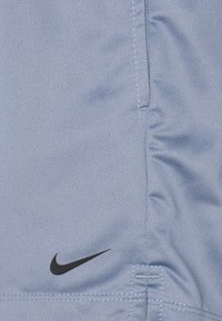 Světlé modré sportovní šortky z texturované látky, s černým logem Nike v dolní levé části a viditelnými detaily švů.