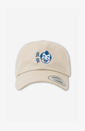 Vaaleanbeige baseball-lippis, jossa on brodeerattu sininen klovnin kasvot, punaisilla poskilla ja mustalla tekstillä. Takana säädettävä hihna istuvuuden varmistamiseksi.