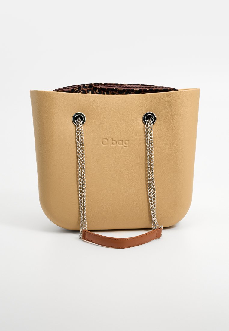 Beżowa torba O o teksturowanej powierzchni, z srebrnymi łańcuszkami jako uchwyty i brązowym skórzanym paskiem akcentującym. Wewnątrz znajduje się podszewka w kolorze panterki.