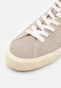 Lys grå ruskinn sneakers med hvite snørebånd, med rund tå, teksturert gummisåle og diskrete sømdetaljer.