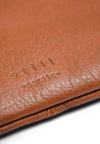Braunes Lederportemonnaie mit strukturierter Oberfläche, geprägt mit "still nordic" und gesteppten Details an den Kanten.