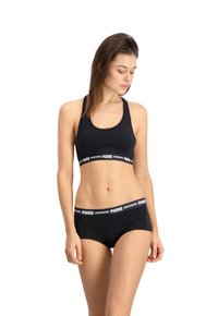 Zwarte sportbeha en bijpassende slip gemaakt van zachte, rekbare stof. Bevat een merk-elastische band met contrasterende witte strepen.