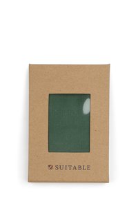 Groen stofmonster ingekapseld in een rechthoekig kraftpapieromlijsting met een transparante plastic venster; heeft "GESCHIKT" gedrukt aan de onderkant.