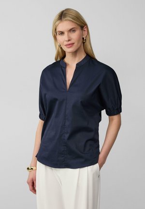 Marineblauwe blouse met een mandarinnekraag, korte pofmouwen met gathering in de manchetten en een rechte zoom. Soepele, lichte stof.