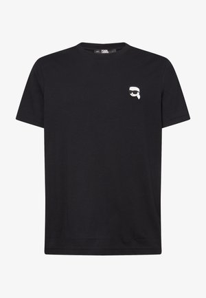 Juodas medvilnės marškinėliai su apvalia iškirpte ir trumpomis rankovėmis. Pavyzdžiuojama maža balta ir pilka grafika kairėje krūtinės pusėje.