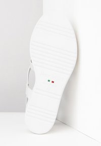 Hvid sandaldso med tekstureret gummi for greb. Har branding "NeroGiardini" og "Made in Italy," med størrelse 37 og farvede italienske flag accenter.