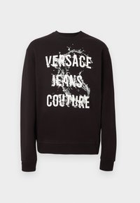 Μαύρο φούτερ με μακριά μανίκια και λευκό κείμενο "Versace Jeans Couture" καθώς και γραφικό με πιτσιλιές νερού στο μπροστινό μέρος. Ριμπ μανσέτες και τελείωμα.