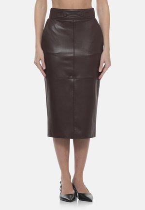 Gonna a tubino in pelle marrone scuro aderente a vita alta con dettaglio di cucitura frontale, indossata con décolleté slingback nere con punta appuntita su sfondo bianco.