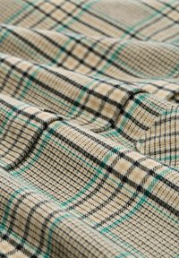 Tessuto beige con un motivo a quadri in nero e turchese, caratterizzato da linee intrecciate e una trama testurizzata per profondità e dimensione.