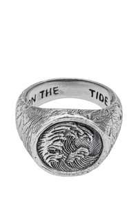 Sidabrinis žiedas su iškilimu bangos formos centre ir tekstūruotais šonais, vidinėje juostos pusėje įrėžtas užrašas „ON THE TIDE“.