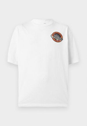 Bijela majica kratkih rukava s malim okruglim zakrpnim prostor-tematskim znakom s raketom i tekstom „High Balance Athletics Since 1908“ na prsima.