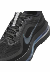 Crne i sive Nike trkaće tenisice s prozračnom mrežicom, prozirnom zračnom potplatom, reflektirajućom trakom na jeziku i Nike swoosh logom sa strane.