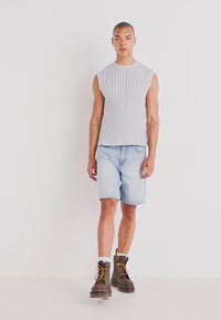 Gray, ribbed sleeveless top paired with light blue denim shorts. Brown lace-up boots with yellow accents. Simple and functional design.